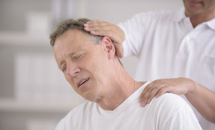 Moški z osteohondrozo vratu na posvetu z ročnim maserjem